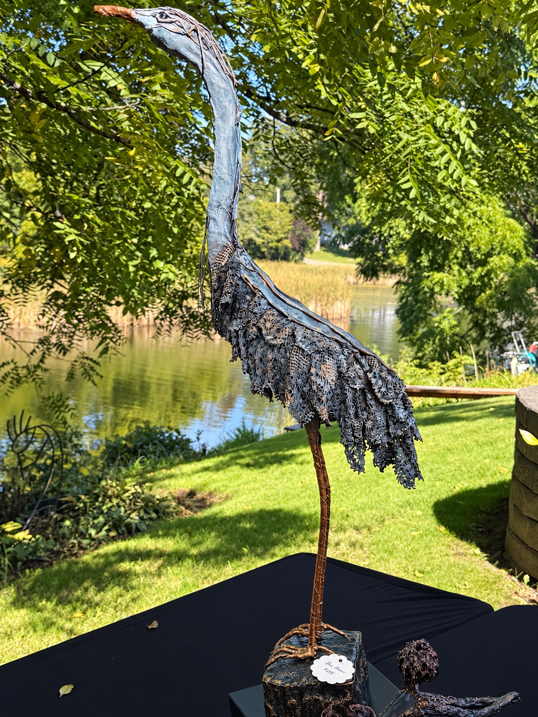 Tall handcrafted heron fabric sculpture beside a pond